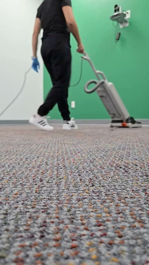 Commercial vacuum moving across an office carpet