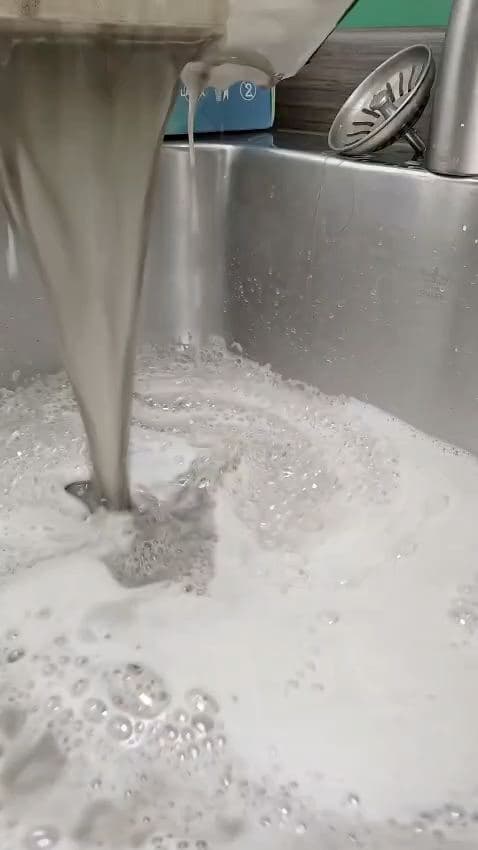 Foam scrub swirling around a stainless steel sink